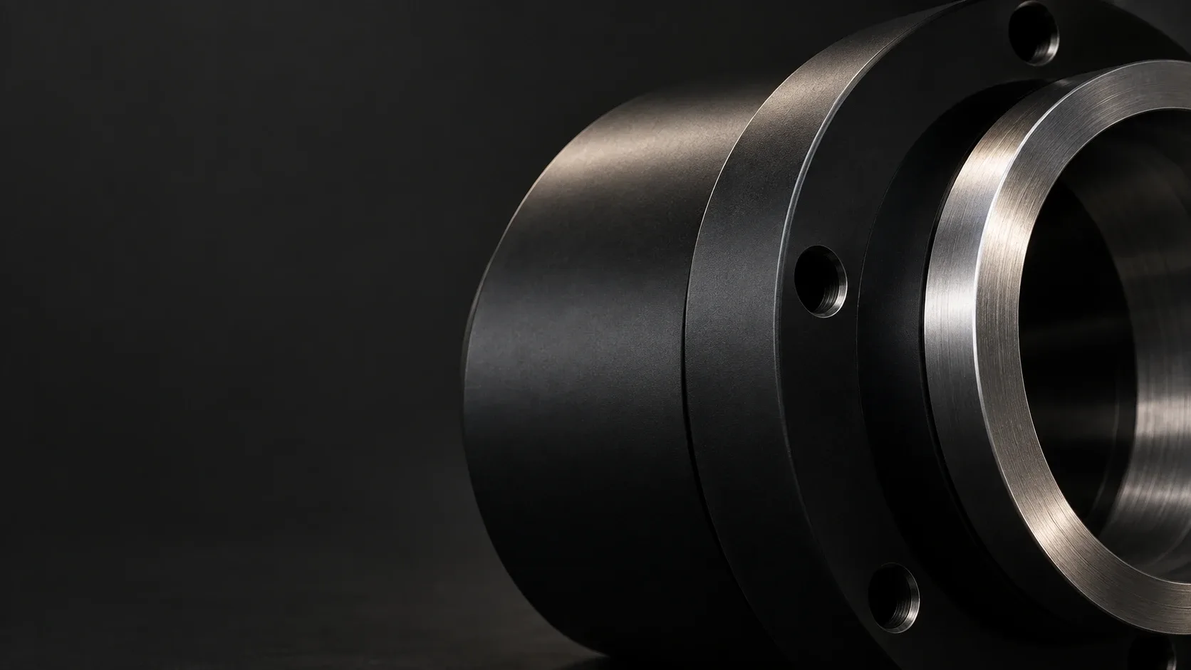 A studio finish study of satin-black cylindrical metal hardware with a silver machined edge against graphite